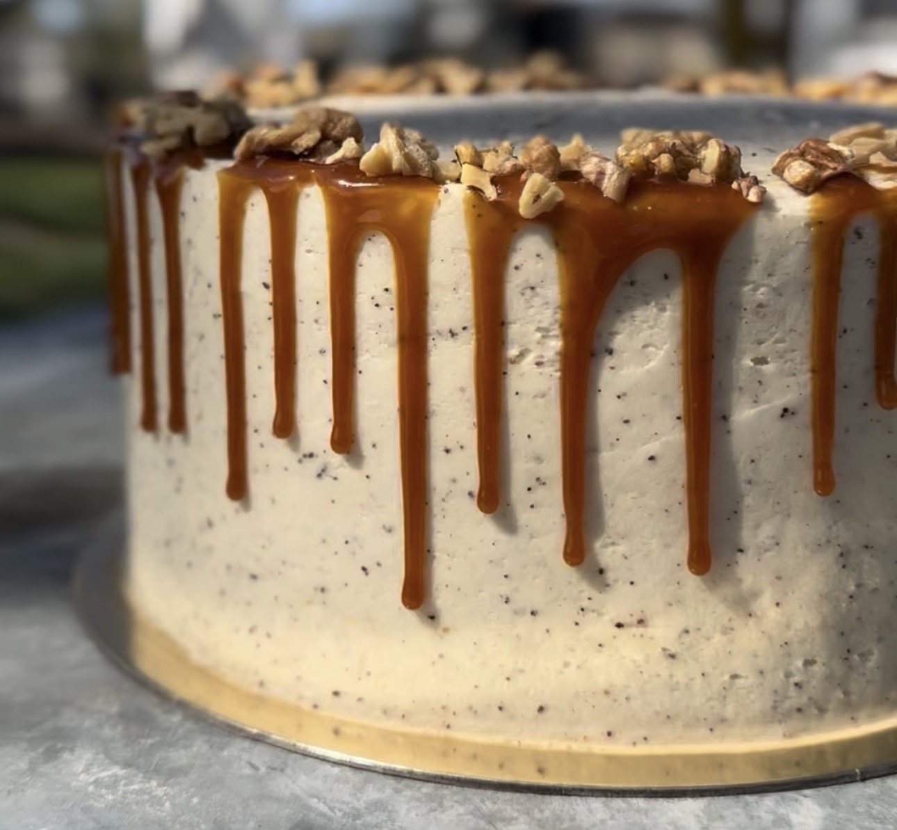 Layered cake with salted caramel dripping down the sides and candied nuts on top