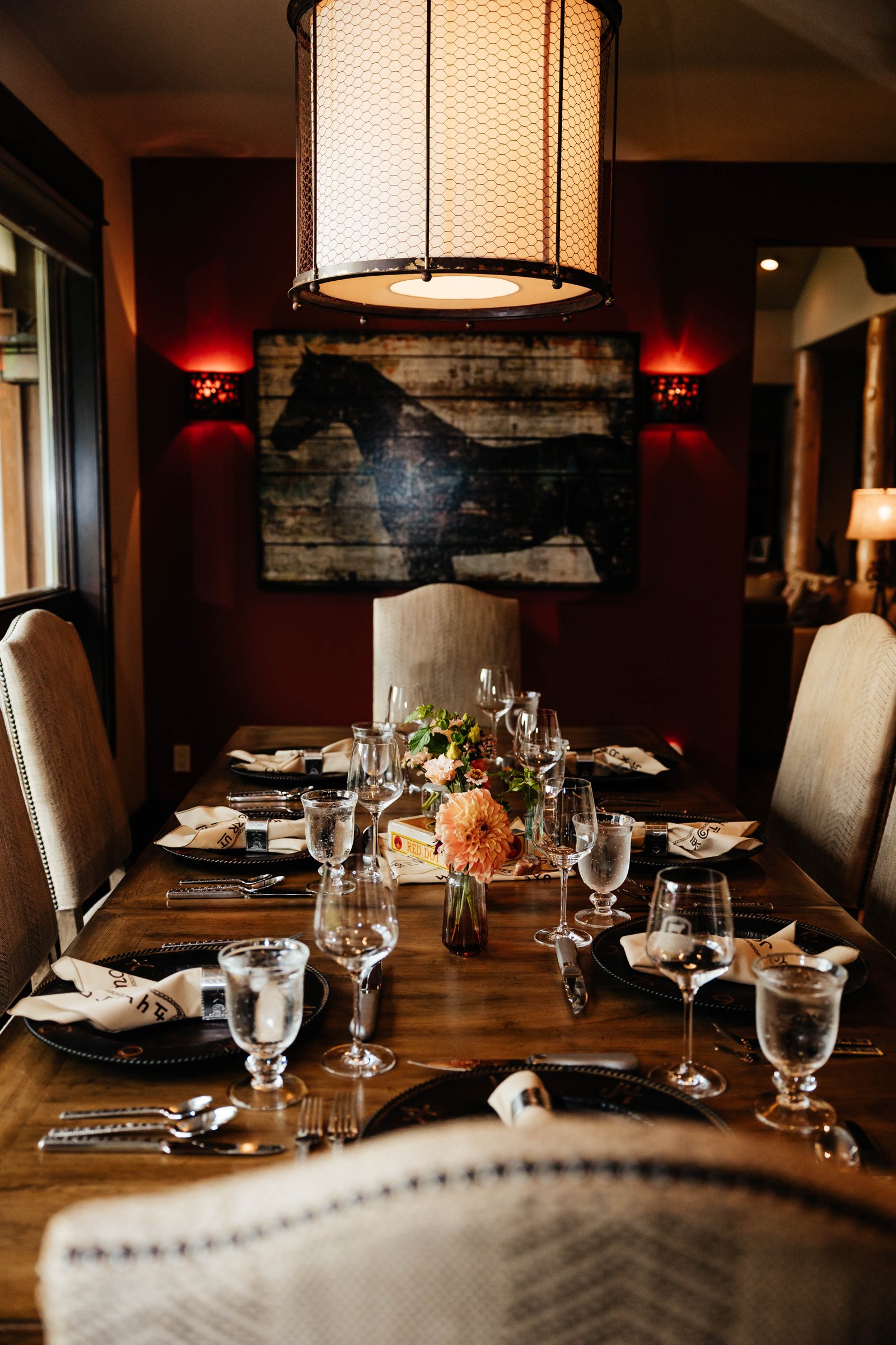 Long table set for a catered dinner with chargers, glassware, and flowers