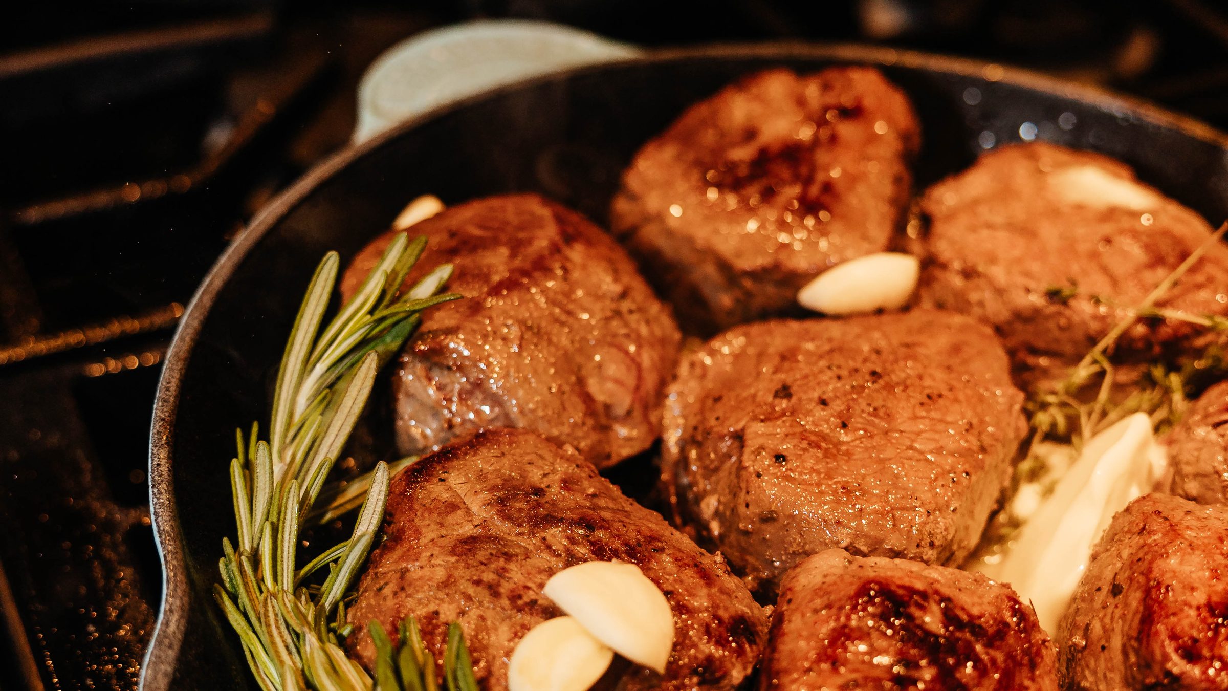 Filets searing in a cast iron pan with rosemary and garlic butter