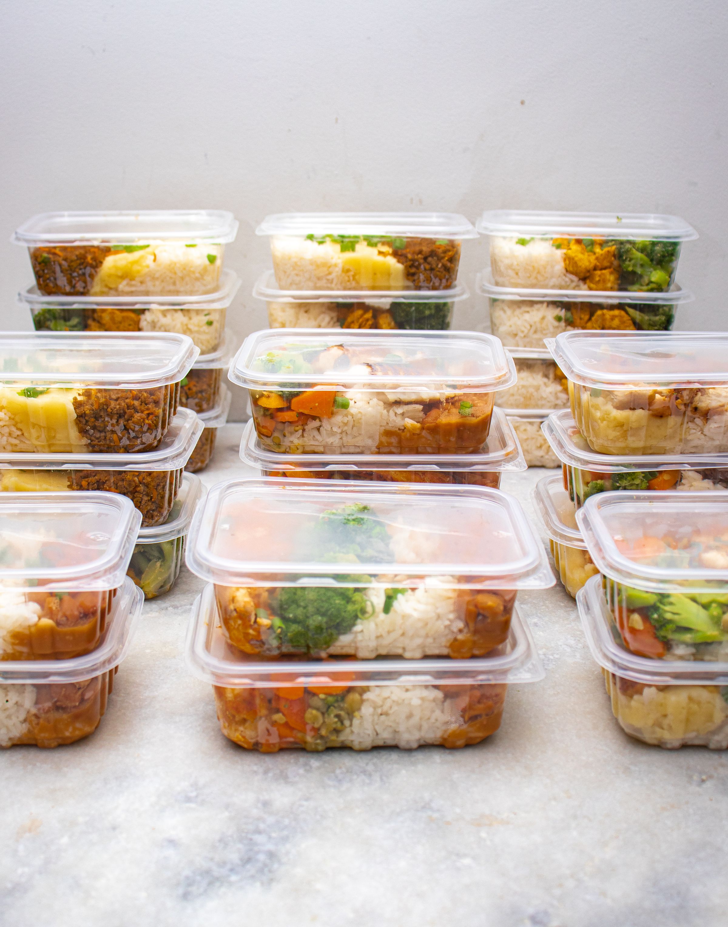 Rows of meal prep containers filled with rice, chicken, and vegetables
