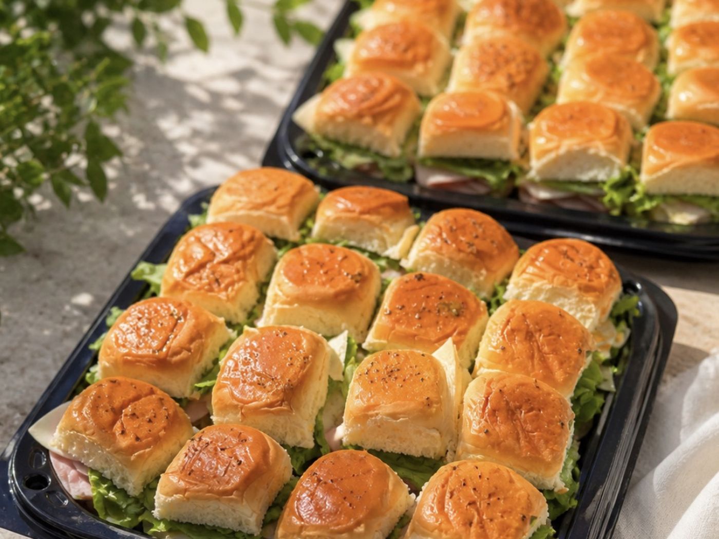 Two trays of sliders on lettuce, ready for pickup