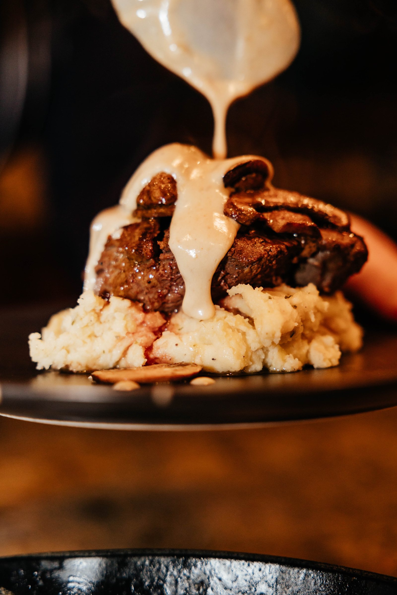 Sauce poured over a seared filet on whipped potatoes